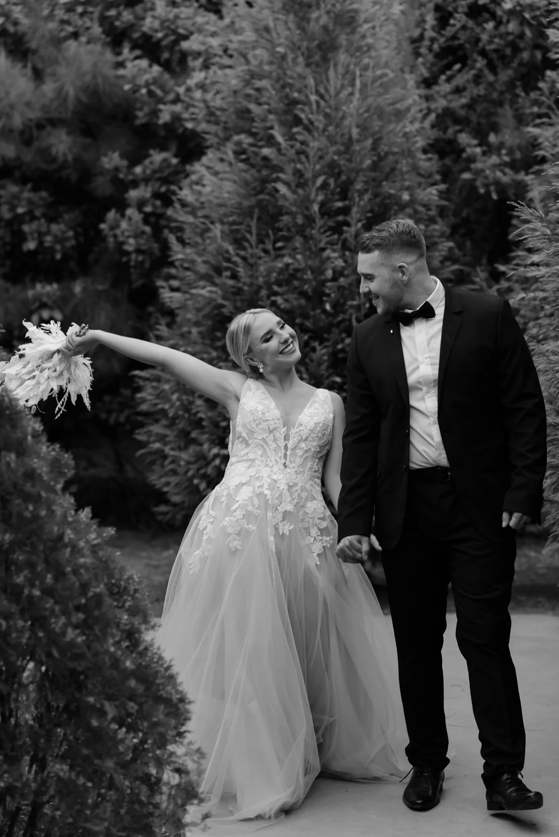 Bride joyfully raising her bouquet in black and white, Pretoria wedding
